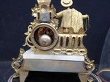 a gold clock with a man and a woman on it