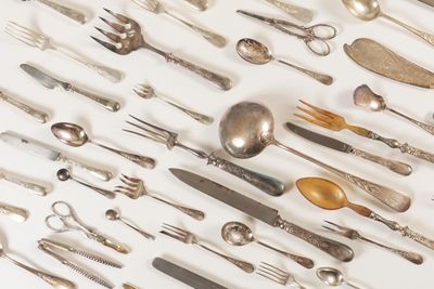 many spoons and forks laid out on a white surface