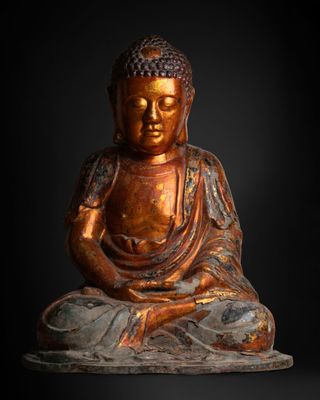 a statue of a buddha sitting on a rock with a black background