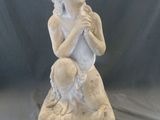 une statue représentant une femme assise sur un rocher, tenant un bébé dans ses bras