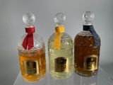 three bottles of perfume sitting on a clear shelf