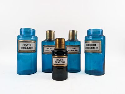 four blue glass bottles are lined up on a white surface