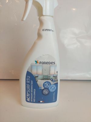 une bouteille de produit nettoyant posée sur un plan de travail, à côté d'un micro-ondes