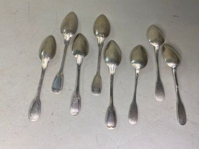 six cuillères en argent sont alignées sur une table