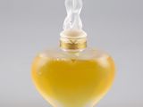 flacon de parfum en verre jaune surmonté d'une petite figurine
