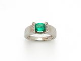 gros plan d'une bague avec une pierre verte et des diamants