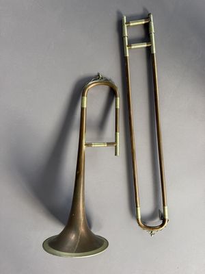 an image of a brass trombone and a trombone stick on a gray surface
