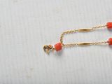 gold plated chain with coral beads on a white background