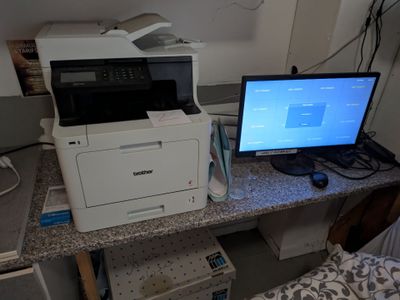 un ordinateur et une imprimante posés sur un bureau dans une pièce