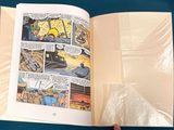 a person holding a comic book open on a table