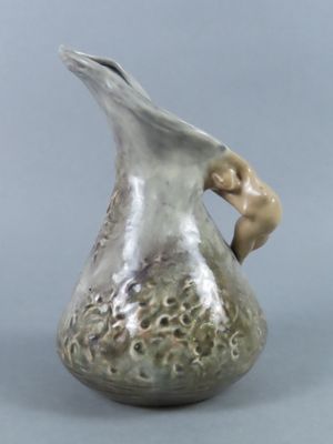a small vase with a bird on it on a table