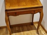 a small wooden desk with a lamp on top of it