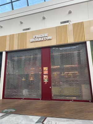 une devanture de magasin avec une porte rouge et une enseigne sur le côté