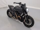 une moto noire garée dans une pièce aux murs blancs