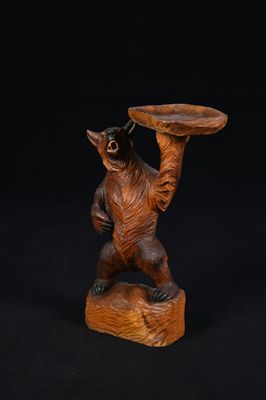 une image représentant une sculpture en bois d'un ours tenant un plateau
