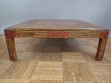 a wooden table with a red top on a wooden floor