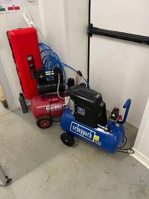 two air compressors sitting next to each other in a garage