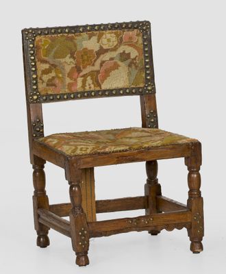 une vieille chaise en bois dont l'assise et le dossier sont recouverts d'un tissu coloré
