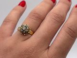 a woman ' s hand holding a gold and diamond ring