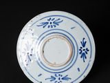 blue and white plate with floral designs on it on a black surface