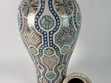 a vase with a lid sitting next to a smaller vase