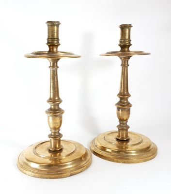pair of antique brass candlesticks on stands on a white background
