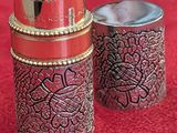 two tins that are sitting next to each other on a red surface