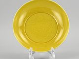 a yellow plate with a design of a dragon on it