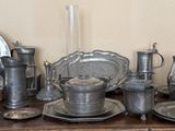 a table with a bunch of silver plates and silver cups