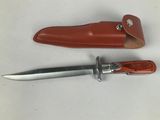 a knife and sheath on the table next to each other