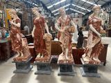 Trois grandes statues de femmes sont posées sur des socles dans un entrepôt