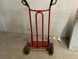 a red hand truck with a black handle in a garage