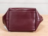 a maroon leather bag sitting on top of a wooden table