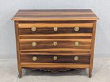 une commode en bois surmontée de ferrures en laiton