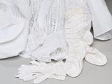 une robe blanche et des gants posés sur une table à côté d'une assiette