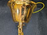 a gold trophy with a green handle on a black background