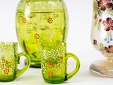 three green glass vases and two cups on a table