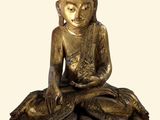 statue d'un Bouddha assis sur un rocher, tenant une fleur dans la main
