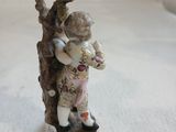 une figurine représentant un garçon tenant un chat dans les branches d'un arbre