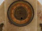 a clock on top of a marble stand with a bird on it