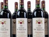six bottles of wine are lined up in a row on a white surface
