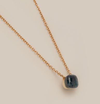 un collier en or avec une pierre bleue suspendue à une chaîne