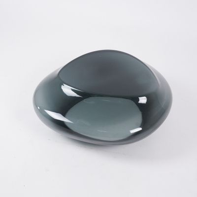 a black glass bowl with a gray base on a white surface