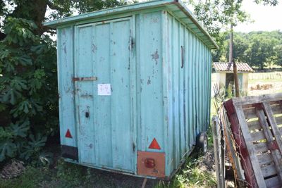 a small blue shed sitting in the middle of a field