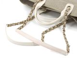 beige and white bag with chain handles on a white surface