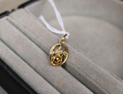un collier en or orné d'un oiseau, présenté dans un coffret