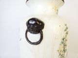 un vase blanc orné d'une tête de lion noire