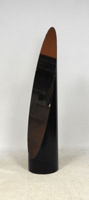 une sculpture représentant un bateau, de couleur noire et marron, posée sur une surface blanche