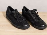 a pair of black sneakers sitting on top of a wooden table