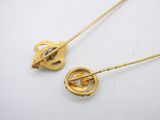 two gold tone brooches with a heart shaped broocher